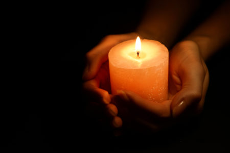 Lit candle in hands of trafficking victim