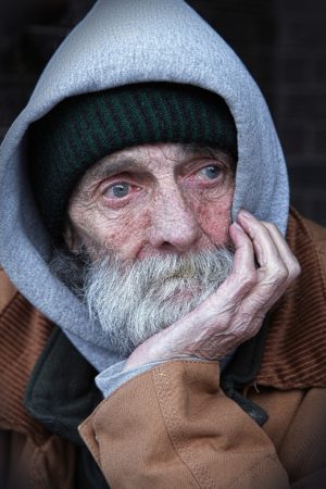 Homeless man with grey beard wearing hoodie
