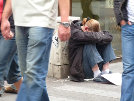 homeless young woman with head down